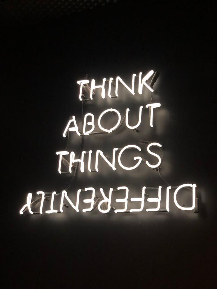 why-choose-us A glowing neon sign displaying an upside-down motivational quote against a dark background.